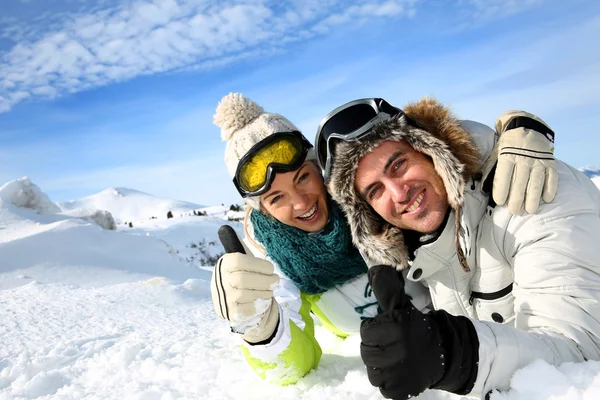 Pareja de esquiadores tumbados en la nieve — Foto de Stock