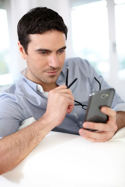 Hombre sentado en el sofá y usando el teléfono inteligente —  Fotos de Stock