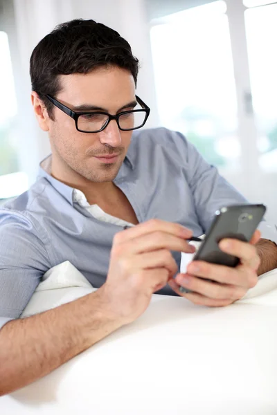 Mann sitzt auf Sofa und benutzt Smartphone — Stockfoto