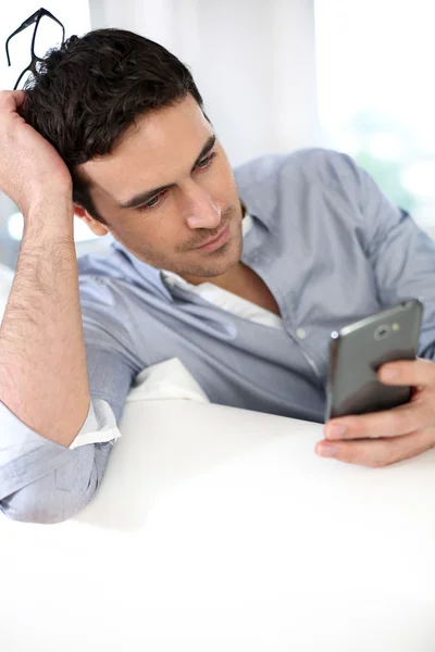 Man sitting in sofa and using smartphone — Stock Photo, Image