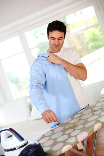 Мужчина гладит рубашку перед уходом на работу — стоковое фото