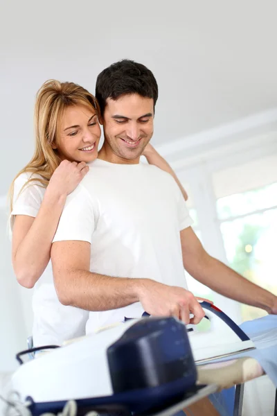 Girl bothering boyfriend while ironing shirt — Stock Photo, Image