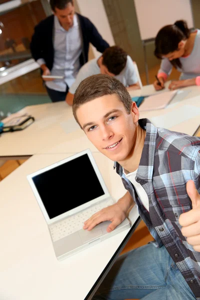 Studente con computer portatile mostrando pollice in su — Foto Stock