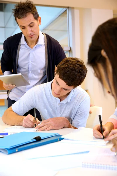 Lärare tittar på eleverna skriva tentamen — Stockfoto