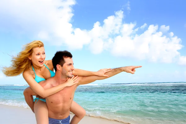 Man giving piggyback ride to girlfriend at the beach Stock Image