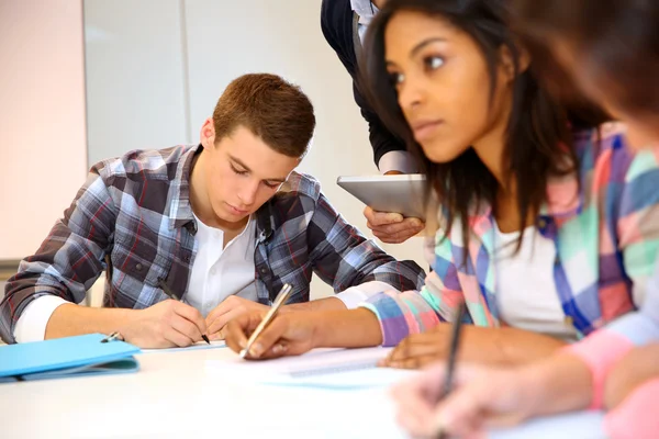 Groupe d'adolescents en classe qui passent un examen Photos De Stock Libres De Droits