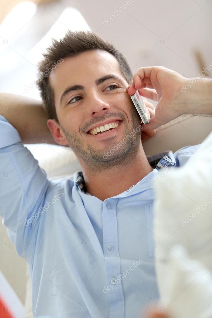 Relaxed young man talking on the phone in sofa