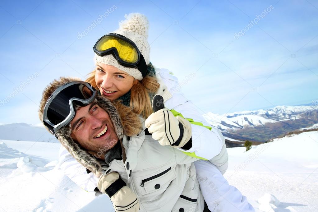 Skier at the mountain giving piggyback ride to girlfriend