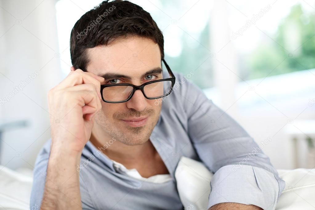 Good-looking man with eyeglasses sitting on sofa