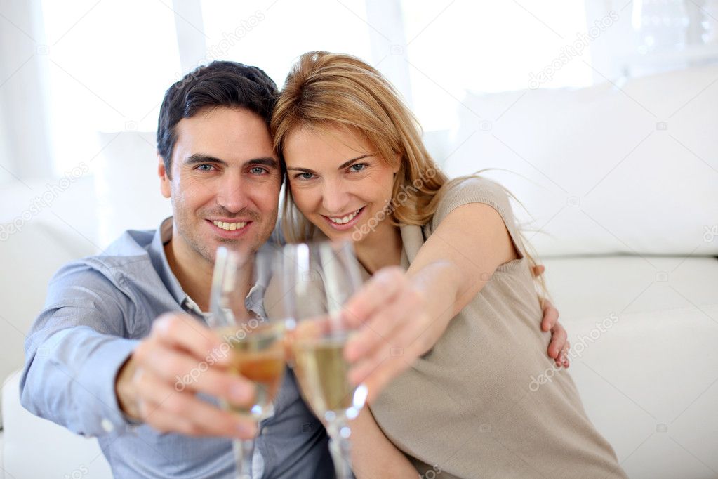 Cheerful couple celebrating with glass of sparkling wine