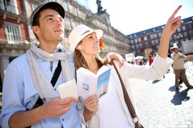 Tourists walking in La Plaza Mayor with traveler guide clipart