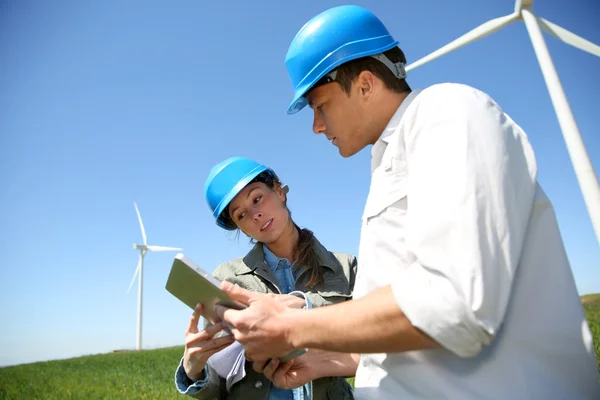 Ingénieurs regardant le site des éoliennes avec tablette — Photo