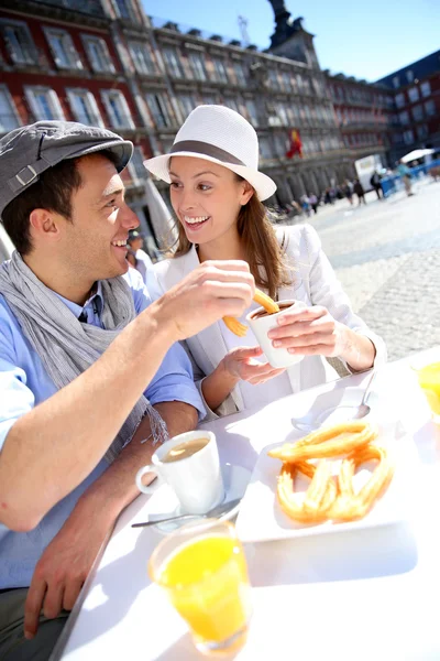 Cheerful couple of tourists eating churros in Madrid — Stock Photo, Image