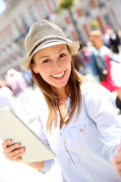 Veselá dívka s kloboukem pomocí tabletu ve městě — Stock fotografie