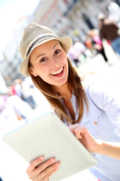 Cheerful girl with hat using tablet in town — Stock Photo, Image