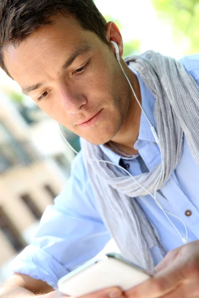 Ragazzo bello utilizzando smartphone e auricolari — Foto Stock