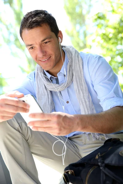 Jóképű srác segítségével okostelefon és fülhallgató — Stock Fotó
