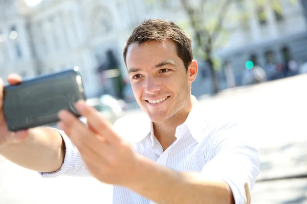 Uomo sorridente che si fotografa con lo smartphone — Foto Stock