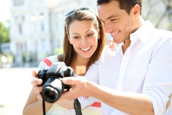 Pareja feliz mirando fotos en la cámara de fotos —  Fotos de Stock