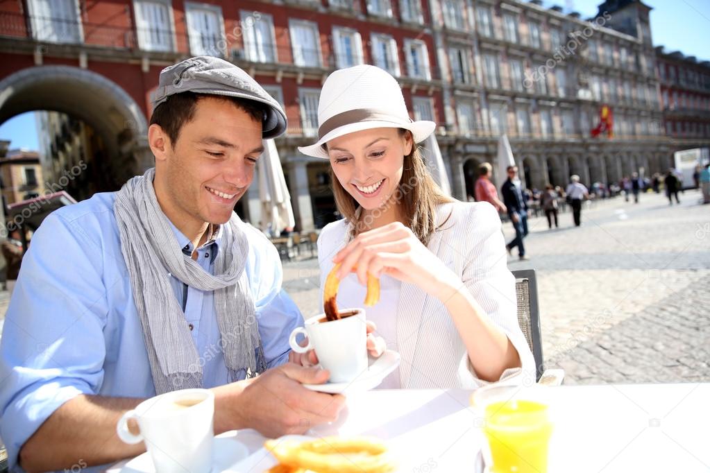 Cheerful couple of tourists eating churros in Madrid