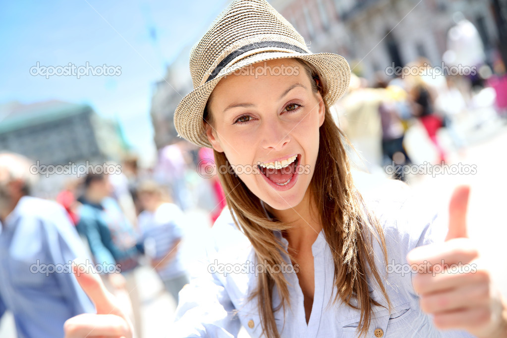 Portrait of cheerful girl in town showing thumbs up