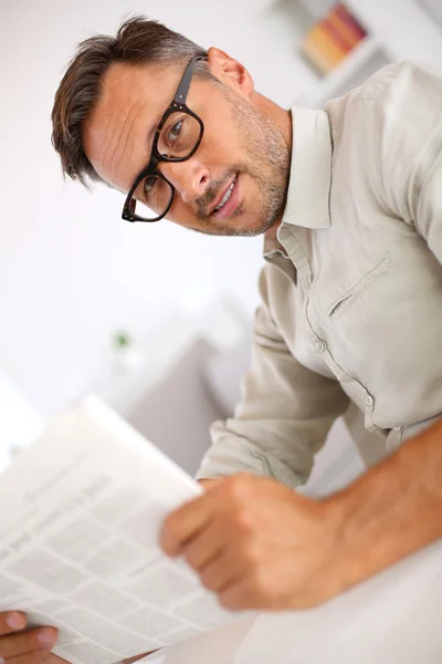 Хлопець з окулярами читає газету — стокове фото