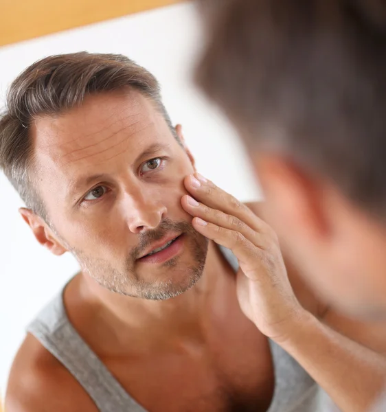 Homme dans la salle de bain appliquant des cosmétiques sur son visage — Photo