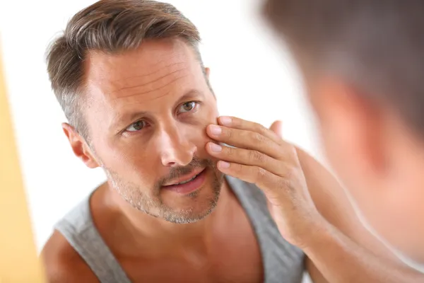 Homme dans la salle de bain appliquant des cosmétiques sur son visage — Photo