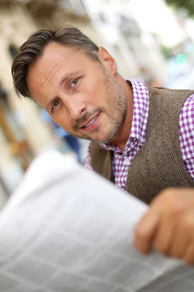 Hombre leyendo el periódico en un banco público — Foto de Stock