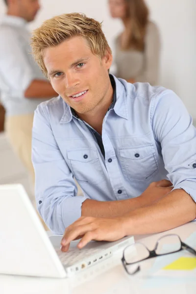 Uśmiechający się atrakcyjny młody człowiek w biurze — Zdjęcie stockowe