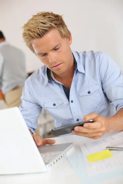 Hombre trabajando con el ordenador portátil y smartphone — Foto de Stock