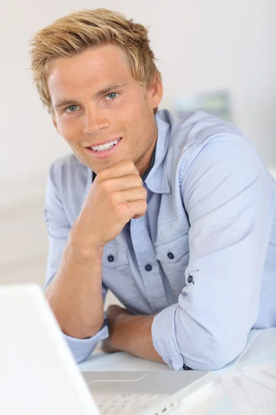 Salesman sitting in front of laptop in office — Stock Photo, Image