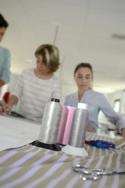 Sytråd och folk i bakgrunden — Stockfoto