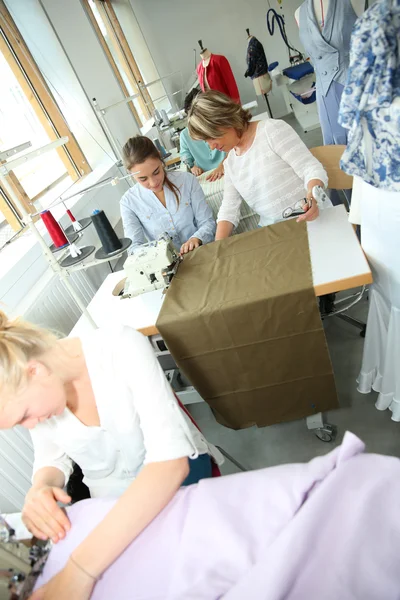 Kvinna i klädsömnad klass hjälpa student — Stockfoto