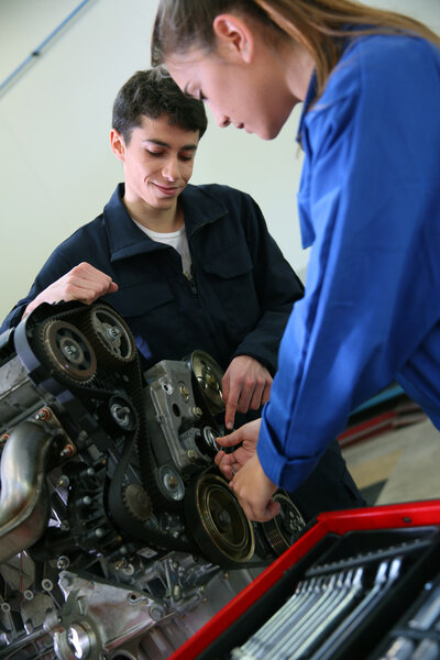 Student in mechanics working on car engine