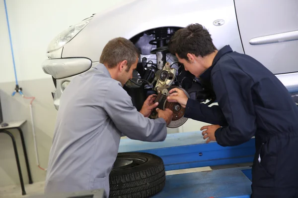 Instructor que muestra al estudiante cómo cambiar los frenos del coche — Foto de Stock