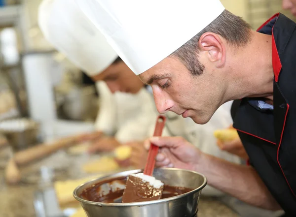 Chef in pastry looking at chocolate cake mixing — Stock Photo, Image