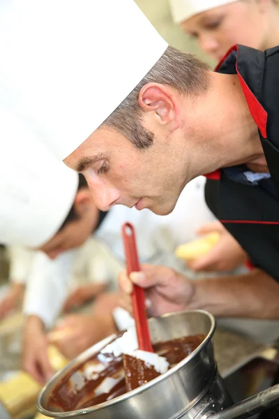 Chef in pastry looking at chocolate cake mixing — Stock Photo, Image