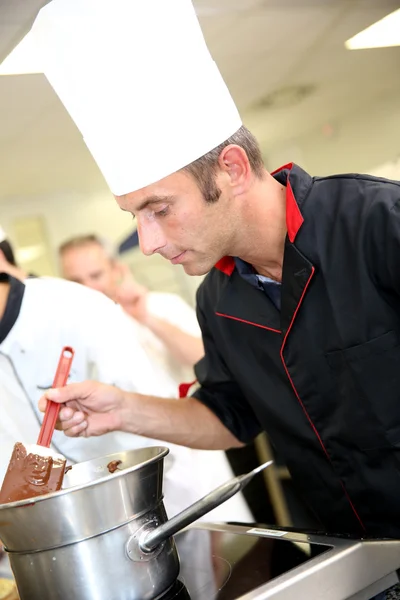 Kock i bakverk tittar på chokladkaka blandning — Stockfoto