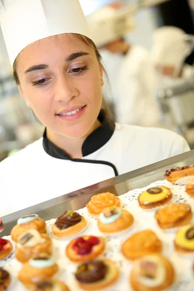 Cocinero pastelero sosteniendo bandeja de pasteles — Foto de Stock