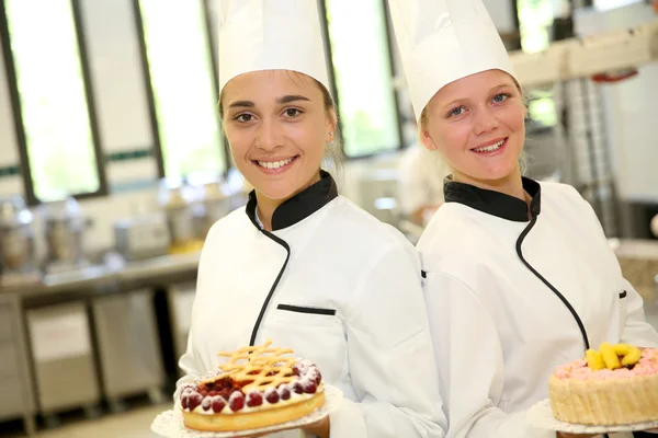 Estudantes meninas em pastelaria segurando bolos — Fotografia de Stock