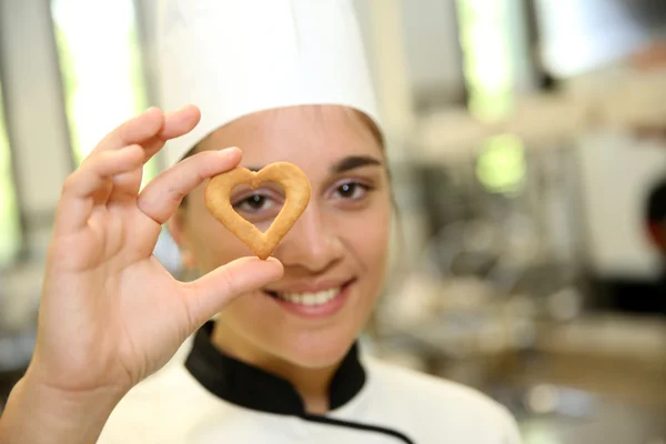 Jeune pâtissier cuisinier tenant cookie — Photo