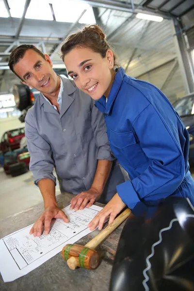 Istruttore con studente ragazza guardando le istruzioni di carrozzeria — Foto Stock