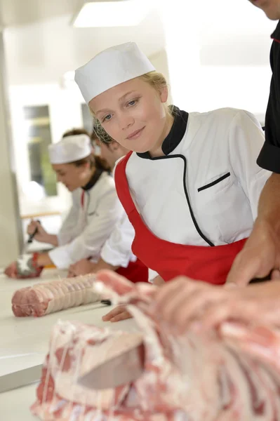 Butcher teaching student with meat cutting — Stock Photo, Image