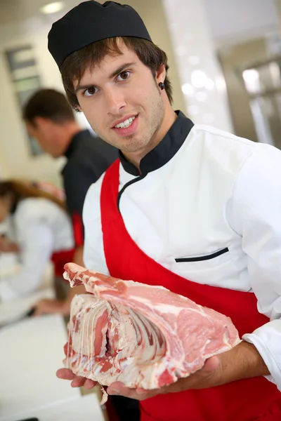 Jeune boucher tenant côtes de veau — Photo