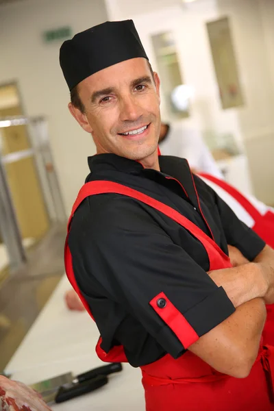 Carniceiro sorridente em pé na cozinha — Fotografia de Stock