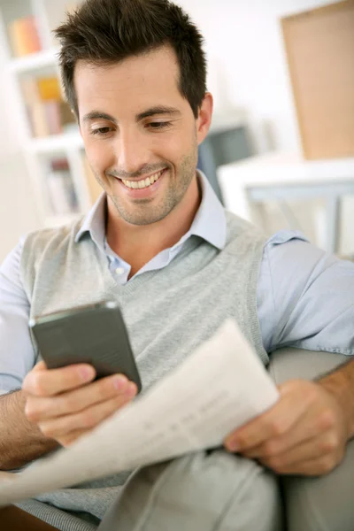 Hombre leyendo noticias tanto en papel como en internet — Foto de Stock