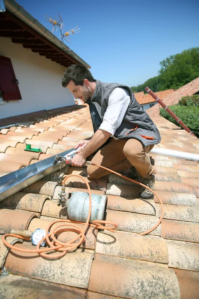 Roofer trabajando en el techo de la casa para arreglar canalón — Foto de Stock