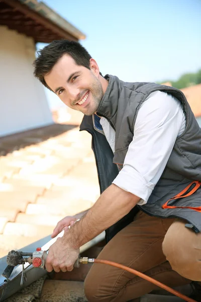 Dachdecker arbeitet an Hausdach, um Dachrinne zu reparieren — Stockfoto