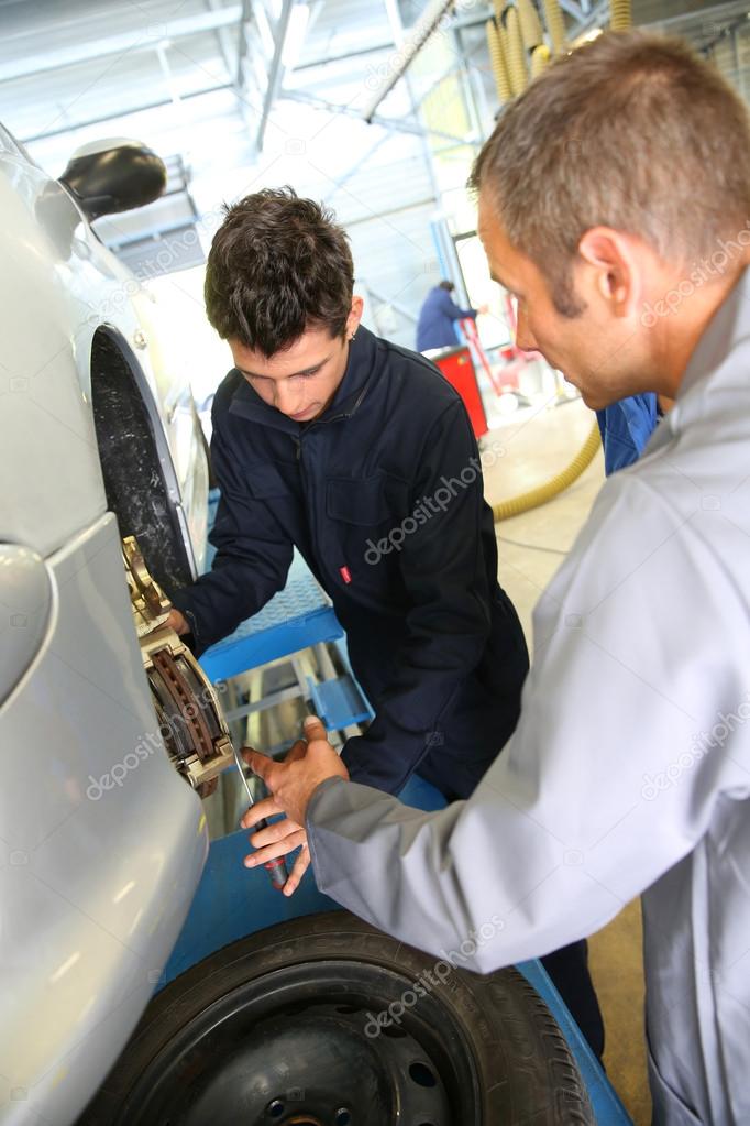 Instructor showing student how to repair car wheel